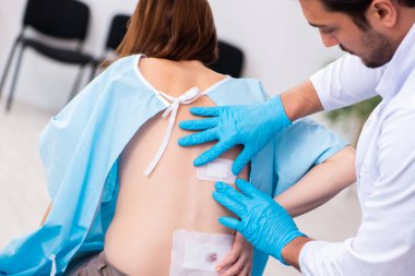 Yaralı genç kadın genç erkek doktoru ziyaret ediyor.