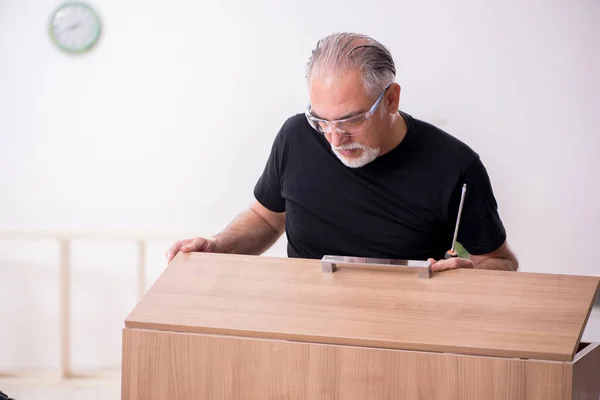 Öreg férfi asztalos, aki beltérben dolgozik — Stock Fotó