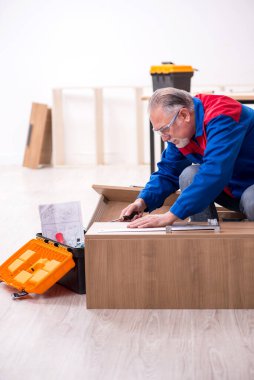 Yaşlı erkek marangoz içeride çalışıyor.