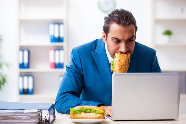 Joven empleado masculino desayunando en el lugar de trabajo — Foto de Stock