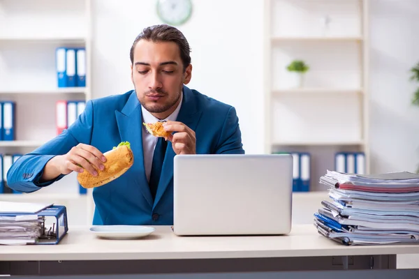 Joven empleado masculino desayunando en el lugar de trabajo — Foto de Stock