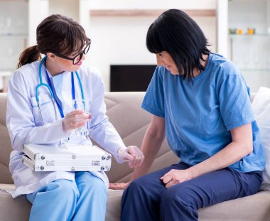 Genç doktor yaşlı kadını muayene etmek için ziyaret ediyor.