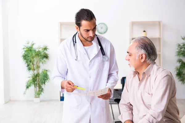 Oude man op bezoek bij jonge mannelijke arts cardioloog — Stockfoto