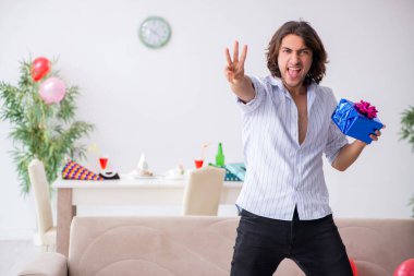 Genç adam doğum gününü evde kutluyor.