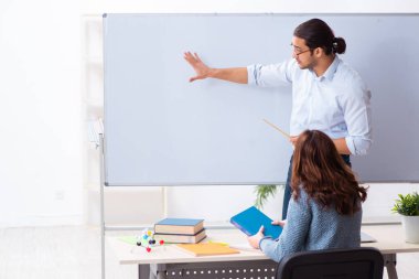 Genç bayan öğrenci ve erkek öğretmen sınıfta.