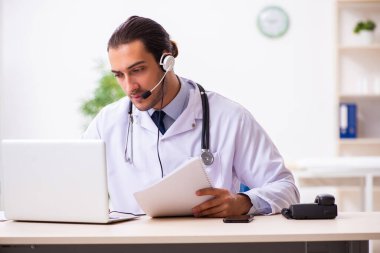 Genç doktor teletıp seansı sırasında hastayı dinliyor.