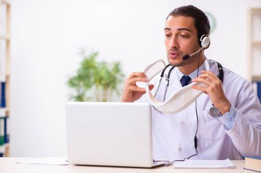 Genç doktor teletıp seansı sırasında hastayı dinliyor.
