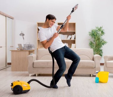 Adam elektrikli süpürgeyle evi temizliyor.