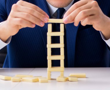 Genç işadamı ofiste domino kulesi inşa ediyor.