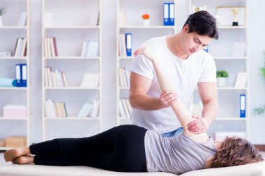 Genç doktor kayropraktik uzmanı kadın hastaya masaj yapıyor.