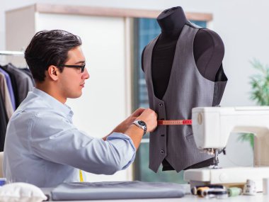Genç terzi yeni elbiseler üzerinde çalışıyor.