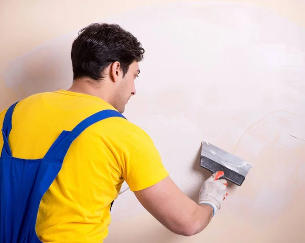 Empleado joven contratista aplicando yeso en la pared — Foto de Stock