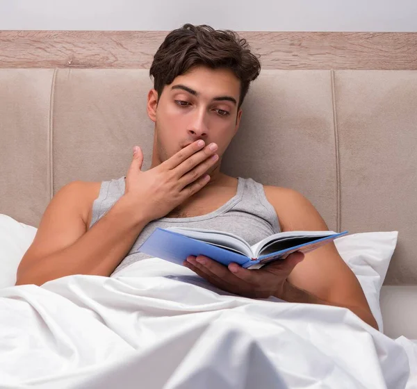 Чоловік читає книгу в ліжку — стокове фото