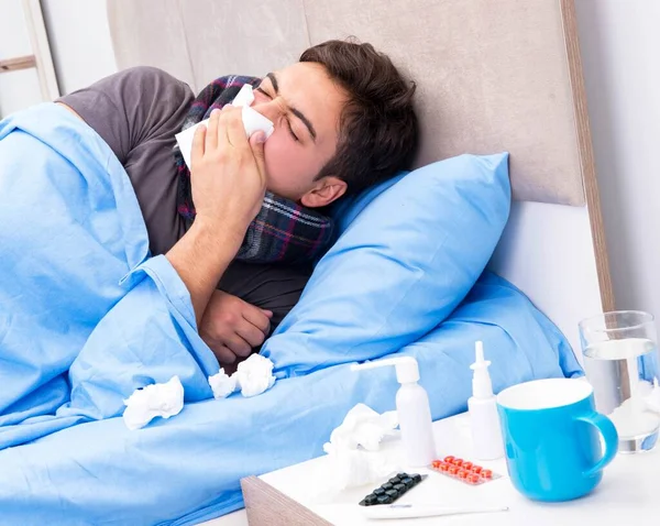 Chory człowiek z grypą leżący w łóżku — Zdjęcie stockowe