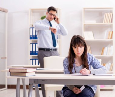 Erkek öğretim görevlisi bayan öğrenciye ders veriyor.