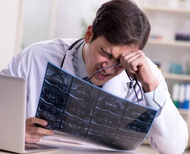 Genç doktor klinikteki röntgen görüntülerine bakıyor.