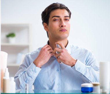 Adam banyoda çalışmak için giyiniyor.