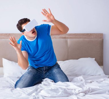Yatakta sanal gerçeklik başlığı takan genç bir adam.
