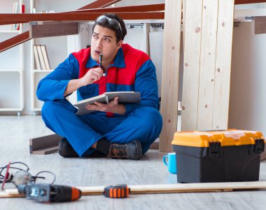 İnşaatta defter planlama yapan genç bir marangoz.