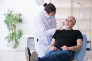 Yaşlı adam estetik ameliyat için genç doktoru ziyaret ediyor.