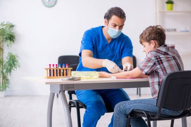 Genç çocuk hastanede doktoru ziyaret ediyor.
