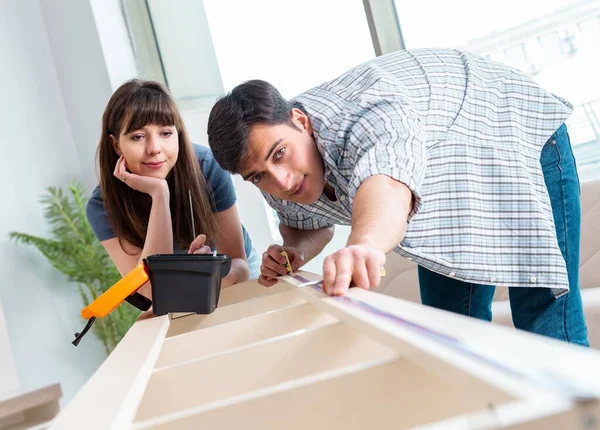 Joven familia ensamblando muebles en casa nueva — Foto de Stock