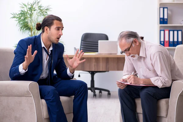 Jongeman op bezoek bij oude mannelijke dokter psycholoog — Stockfoto