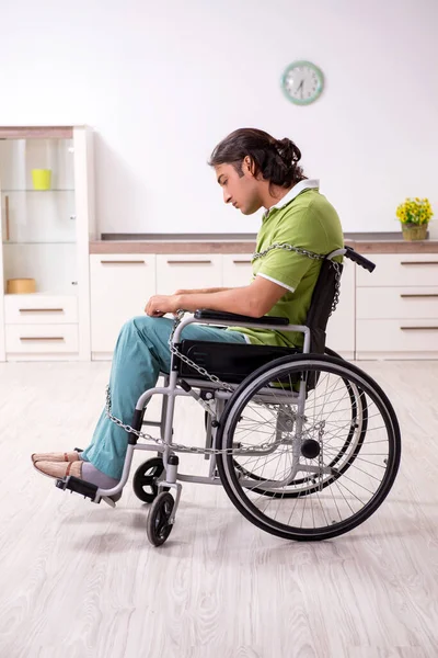 Jeune homme invalide en fauteuil roulant souffrant à la maison — Photo