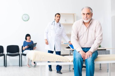 Yaşlı çift genç erkek doktoru ziyaret ediyor.
