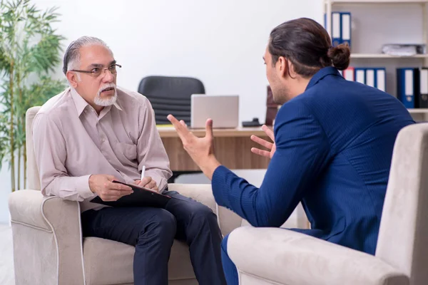 Jongeman op bezoek bij oude mannelijke dokter psycholoog — Stockfoto