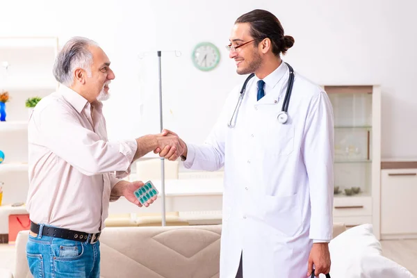 Jeune médecin de sexe masculin visitant un vieux patient à la maison — Photo