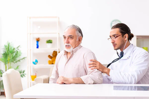 Jonge mannelijke arts bezoekt oude patiënt thuis — Stockfoto