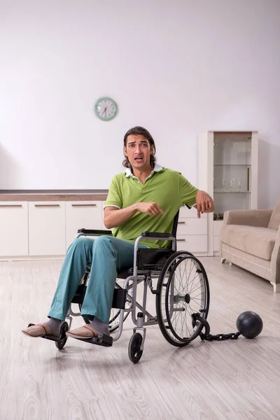 Jovem homem inválido em cadeira de rodas sofrendo em casa — Fotografia de Stock