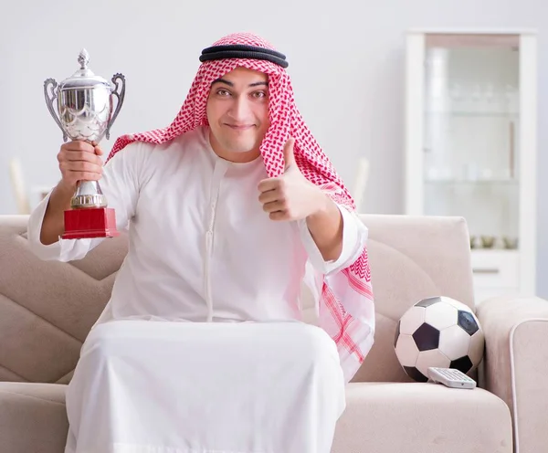 Молодой араб смотрит футбол, сидя на диване — стоковое фото