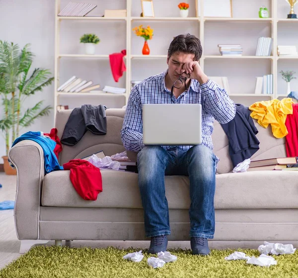 Jeune homme travaillant dans une chambre désordonnée — Photo