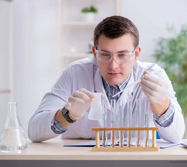 Jeune étudiant chimiste expérimentant en laboratoire — Photo