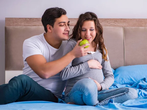 Молода сім'я з вагітною дружиною очікує дитину в ліжку — стокове фото