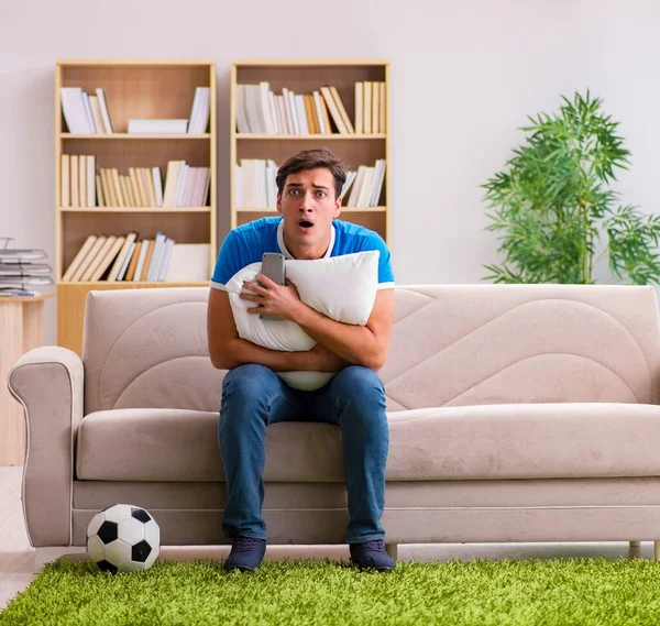 A férfi otthon focit néz, a kanapén ül. — Stock Fotó