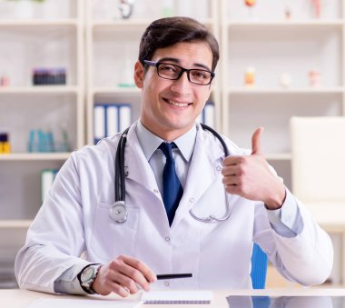 Genç doktor ofiste oturuyor.