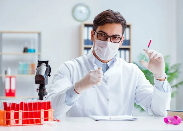 Mladý lékař pracuje v laboratoři pod mikroskopem — Stock fotografie