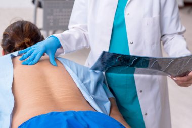 Genç sırtı yaralı bir adam, kadın doktor masörünü ziyaret ediyor.