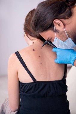 Genç bir kadın erkek doktor dermatoloğunu ziyaret ediyor.