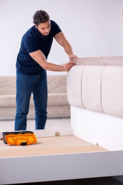 Genç erkek müteahhit eve mobilya kuruyor.