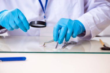 Kanıt için laboratuvarda çalışan yaşlı bir erkek kriminolog.