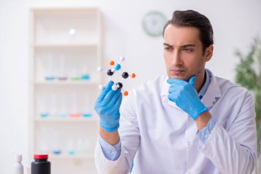 Uyuşturucu sentezi konseptinde genç erkek laboratuvar asistanı