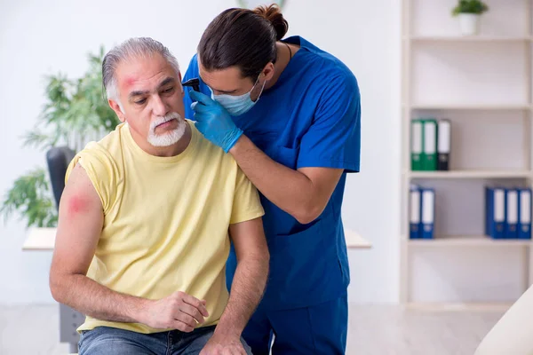 Ferito vecchio visita giovane medico traumatologo maschile — Foto Stock