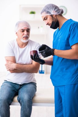 Yaşlı adam estetik ameliyat için erkek doktoru ziyaret ediyor.