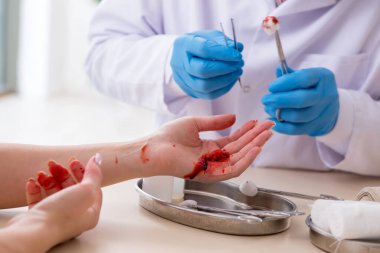 Yaralı kadın erkek doktoru ziyaret ediyor.
