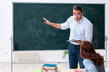 Genç bayan öğrenci ve erkek öğretmen sınıfta.