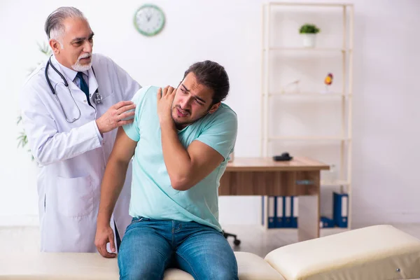 Gewonde jongeman op bezoek bij oude dokter — Stockfoto